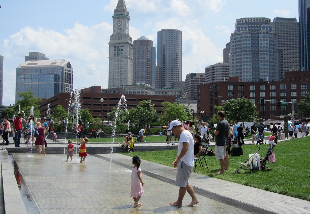 los niños juegan en las fuentes de agua y las familias se sientan en el césped en Rose Kennedy Greenway en Boston