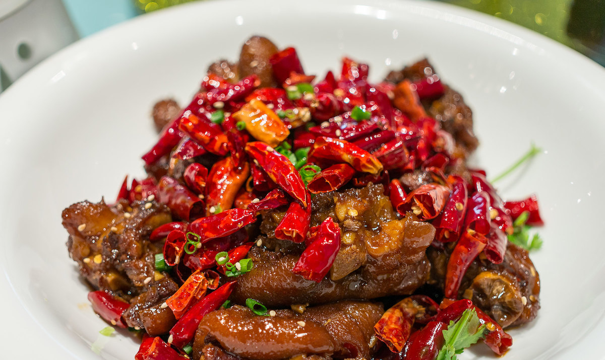primer plano de un tazón blanco lleno de carne de res marinada con chiles rojos picantes