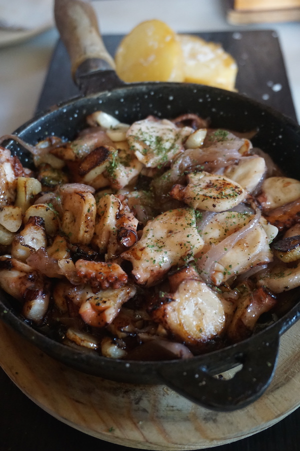 Delicioso pulpo frito, servido en una sartén grande con una guarnición de patatas, es una de las muchas razones por las que Vineria es uno de nuestros restaurantes favoritos en Sevilla.