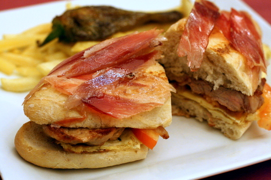 Un favorito local es el clásico sándwich de seranito, que se ve aquí relleno con huevo y tomate, además de jamón y cerdo, y es definitivamente uno de los sándwiches más épicos de Sevilla.