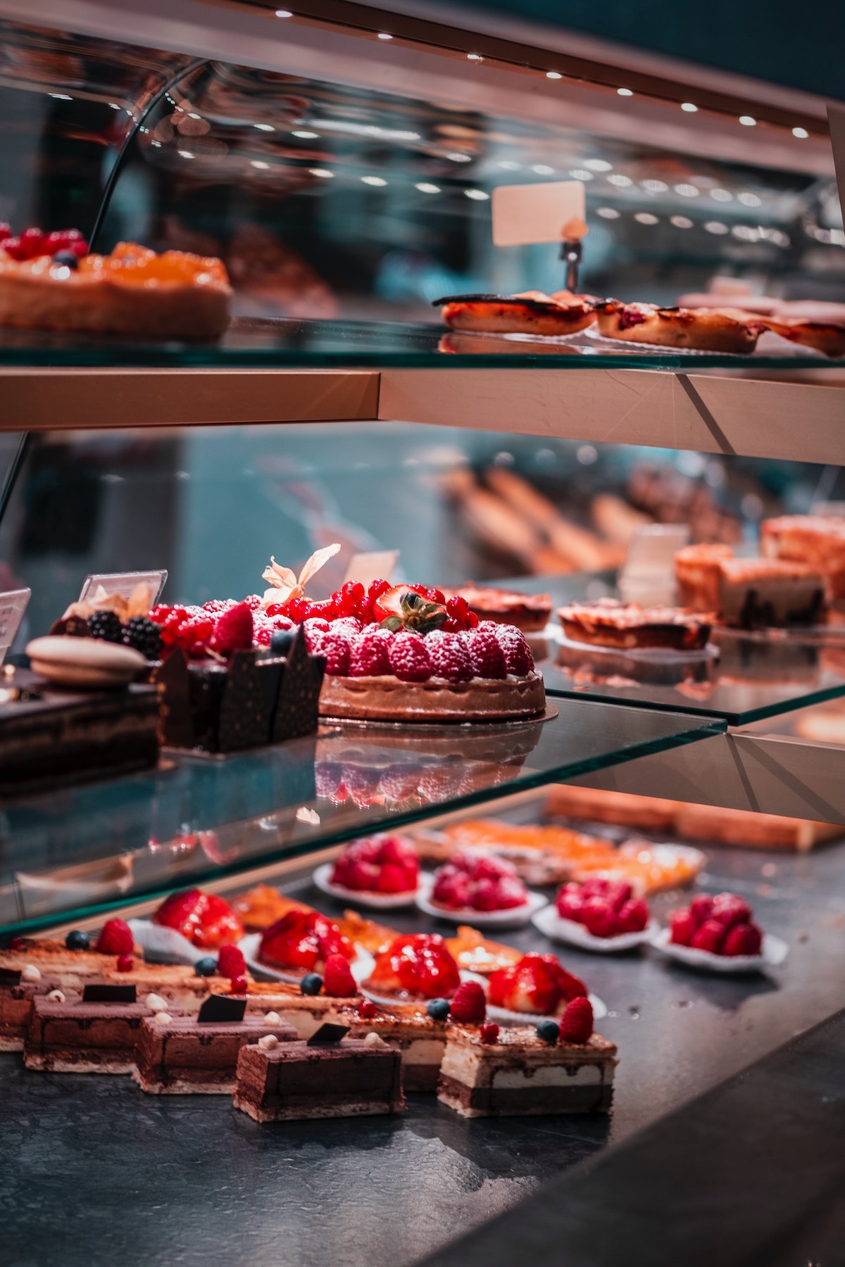 Pequeñas tortas adornadas con fresas y otras frutas en el caso de los expositores de panadería.