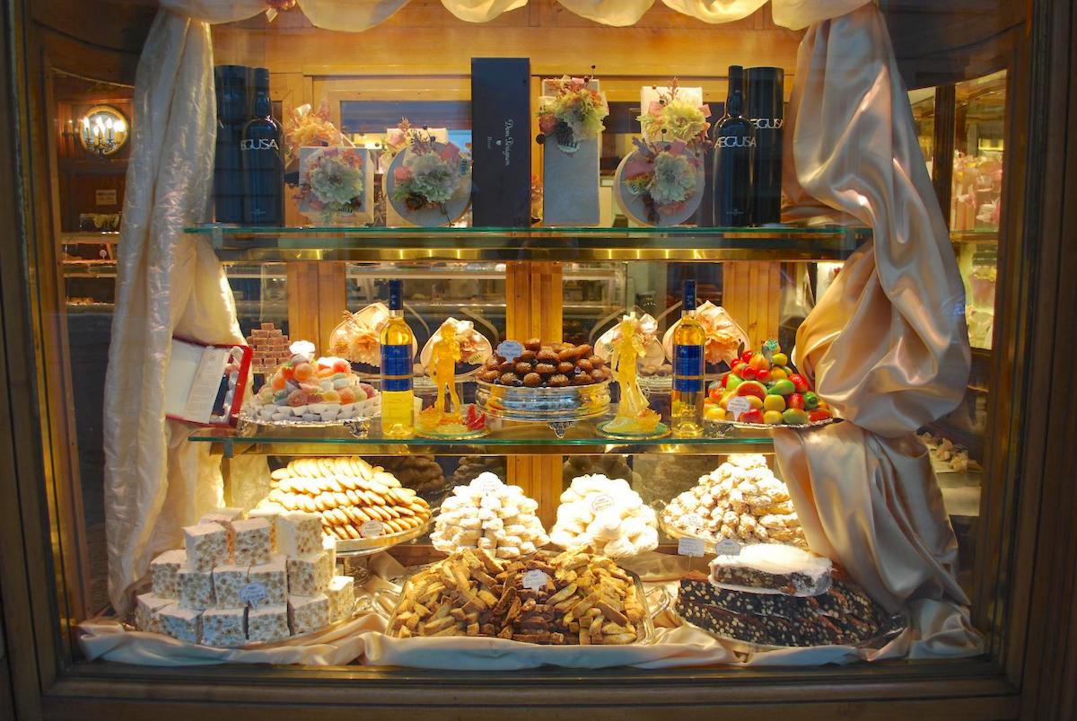 Pasteles y dulces exhibidos en una ventana de panadería.