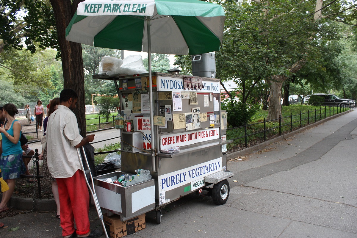 Una tarjeta de comida con escritura y mensajes en un sendero frente a un parque