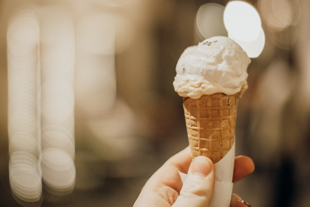 La mano de una persona sosteniendo un cono con una pequeña bola de helado
