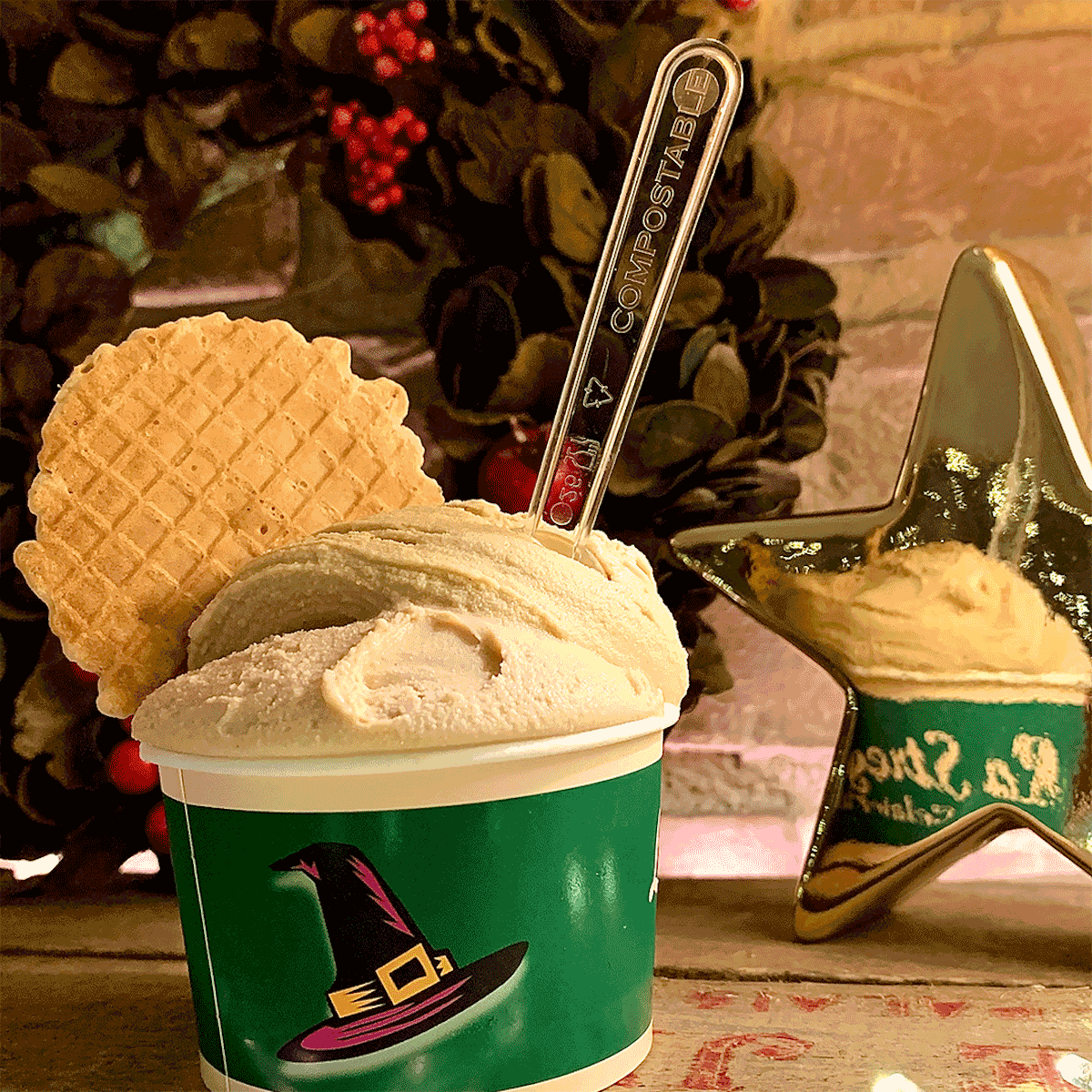 Helado decorado con una galleta fina en un vaso verde con diseño de sombrero de bruja.