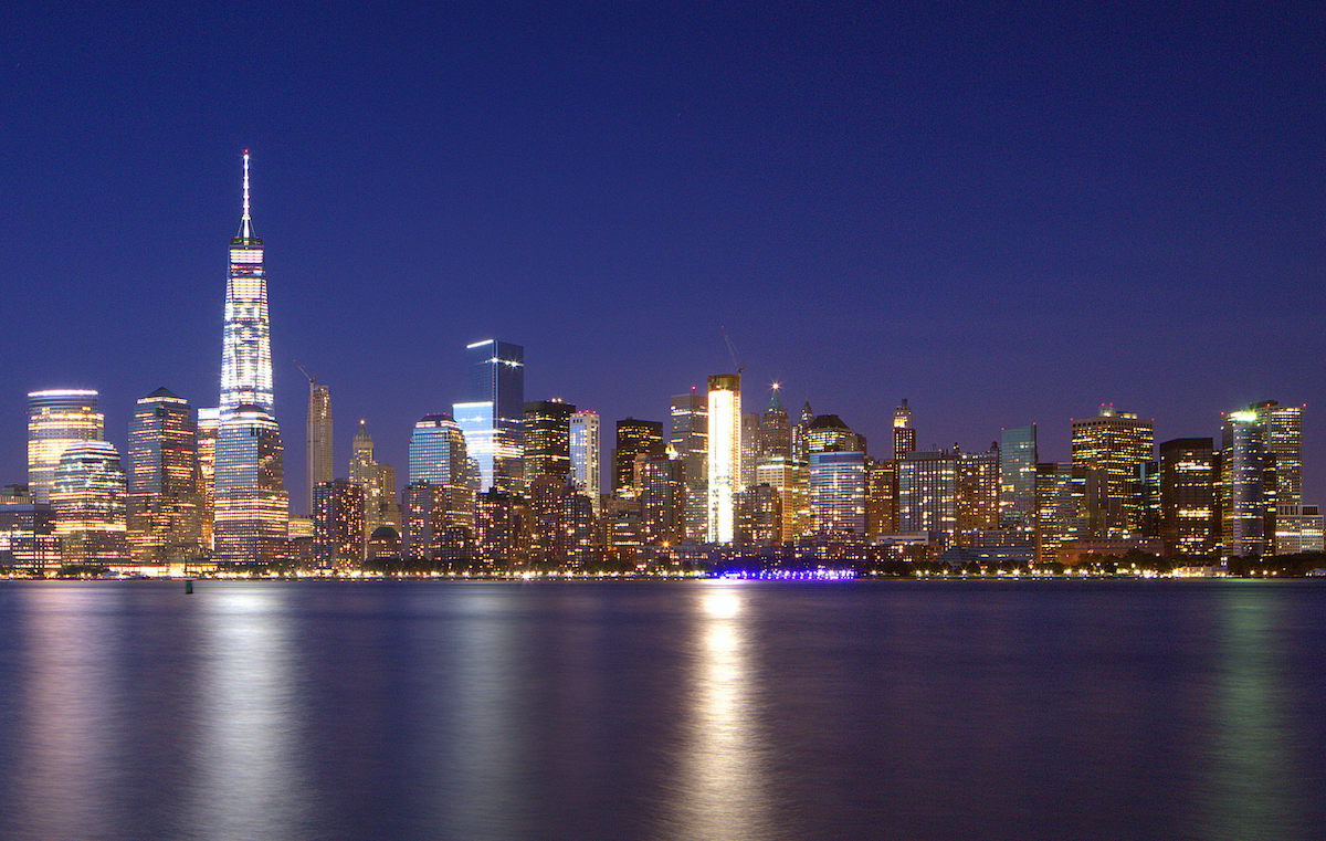 El horizonte de la ciudad de Nueva York se iluminó por la noche visto desde una masa de agua.