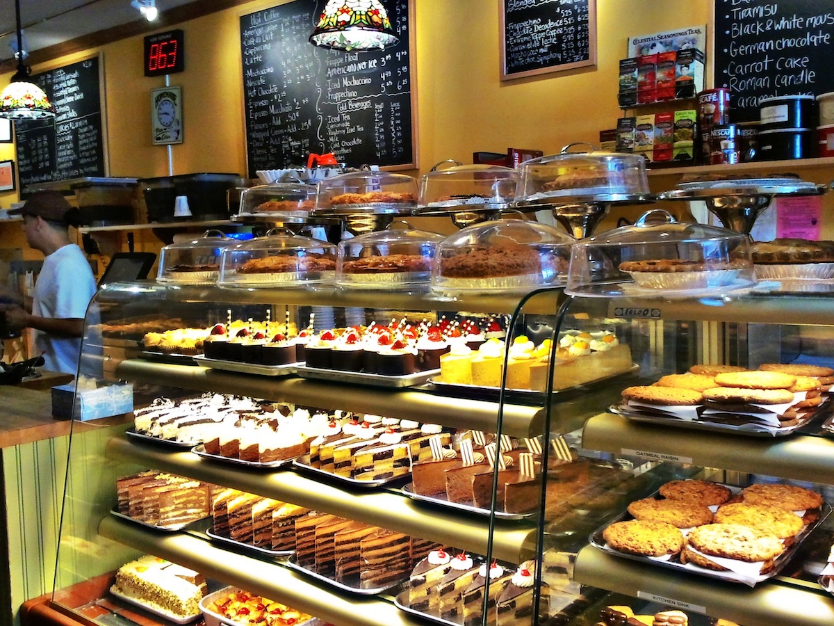 Una variedad de pasteles y otros productos horneados exhibidos en una vitrina en un mostrador de panadería