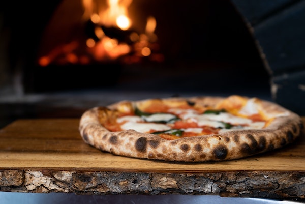 Pizza estilo napolitano frente a un horno