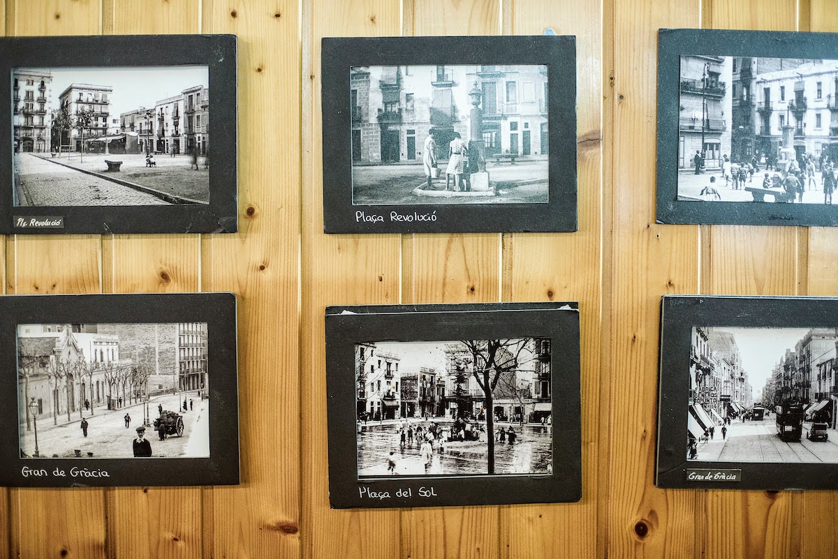 Viejas fotos en blanco y negro de Barcelona cuelgan de una pared con paneles de madera.