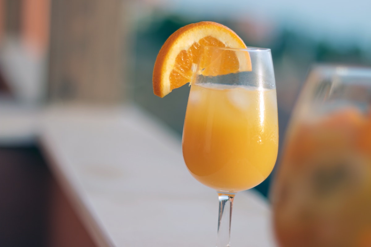 Cierra la copa de vino llena de mimosa y guarnición de rodaja de naranja