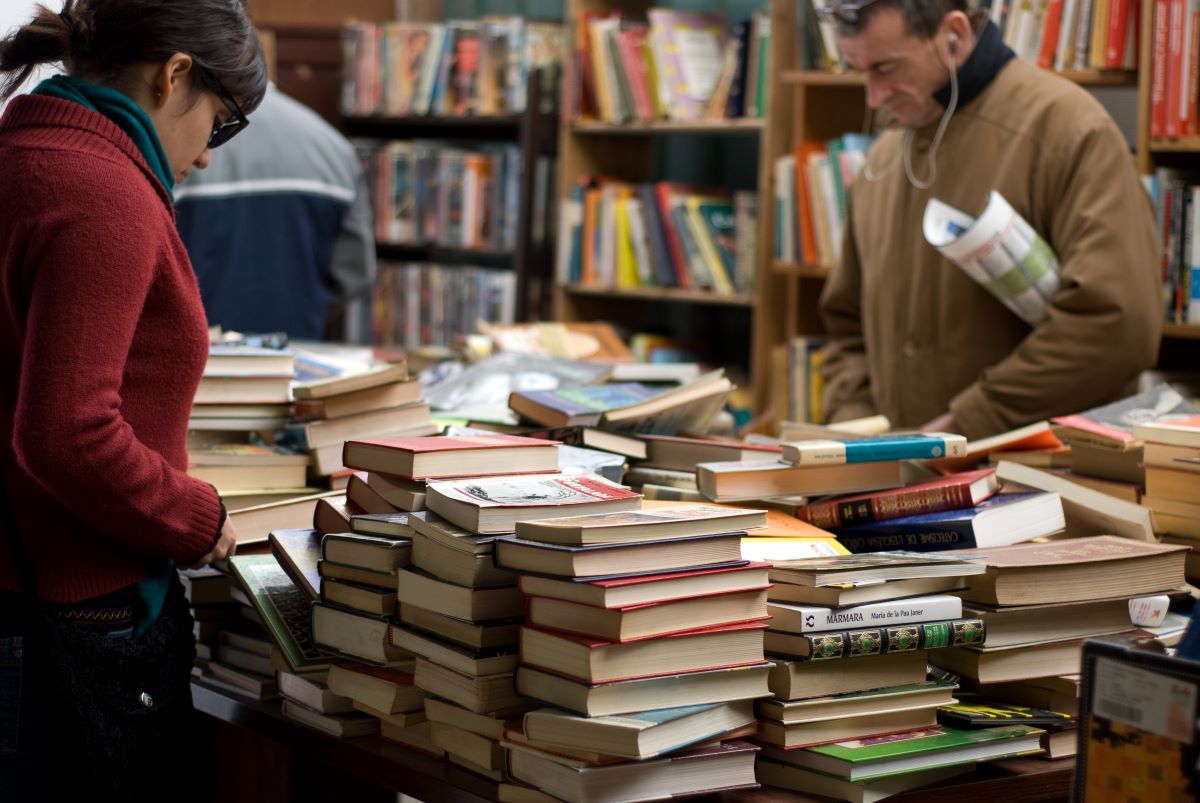 mujer-y-hombre-de-pie-cerca-montones-de-libros