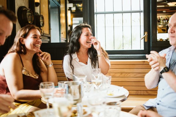 Un grupo de personas comiendo en un restaurante y riendo.