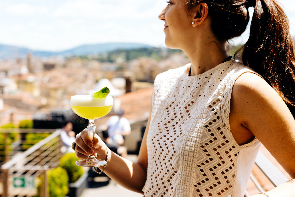 Una mujer con una margarita en un bar en la azotea por encima de Florencia, Italia.